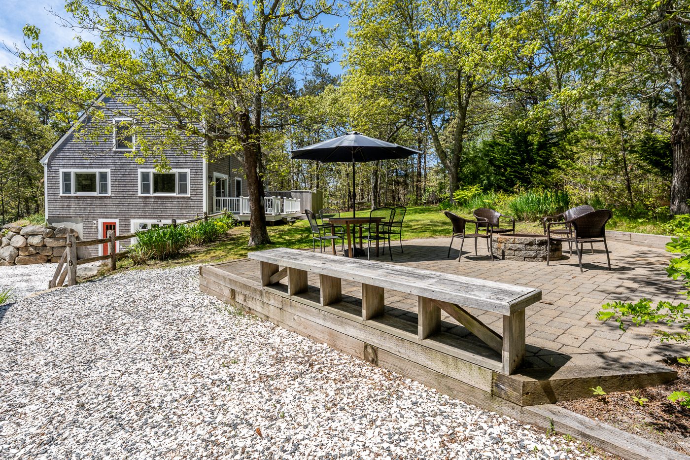 Patio with the fire pit, table and umbrella, the house behind
