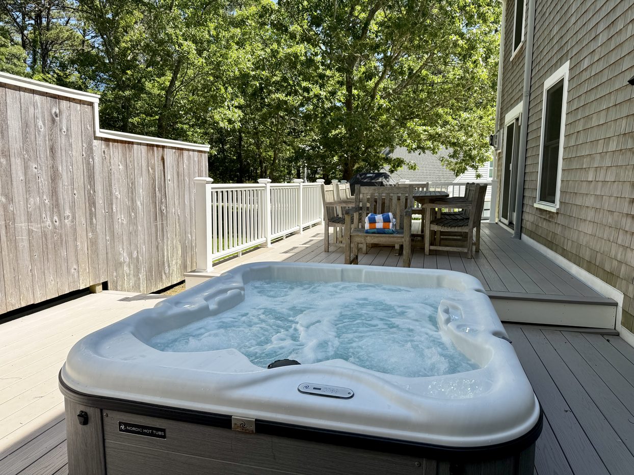 Hot tub bubbling on the deck, with the dining table and trees behind