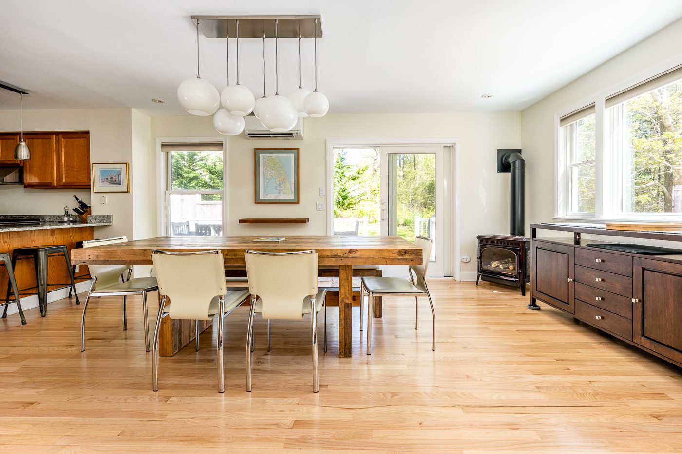 Dining room with a long wooden table under globe lights, a Cape Cod map on the wall and doors to the deck